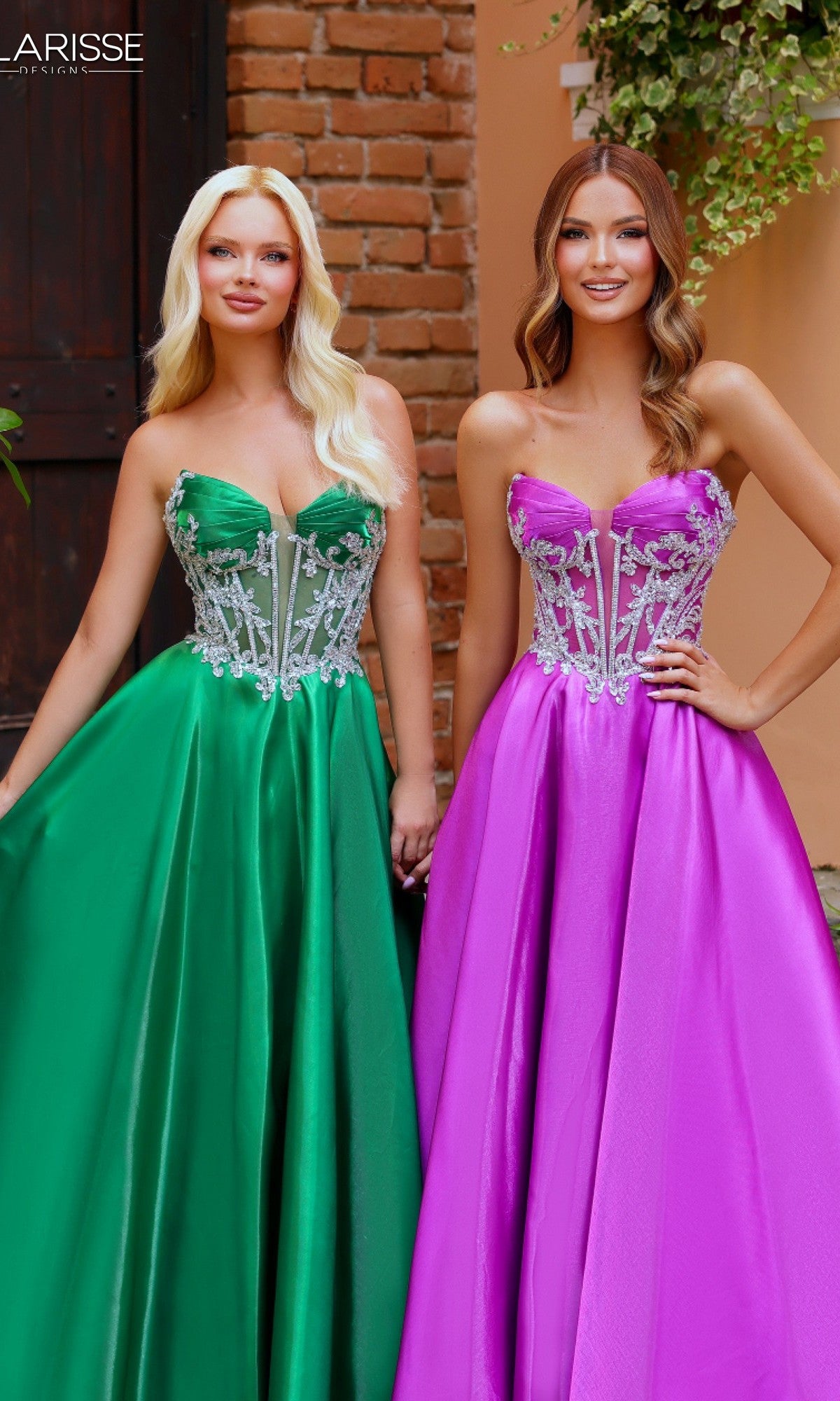 Two women stand side by side in Clarisse Designs 62140 prom ball gowns—one wears green liquid satin, the other purple; both dresses have strapless beaded corset bodices with silver embellishments.